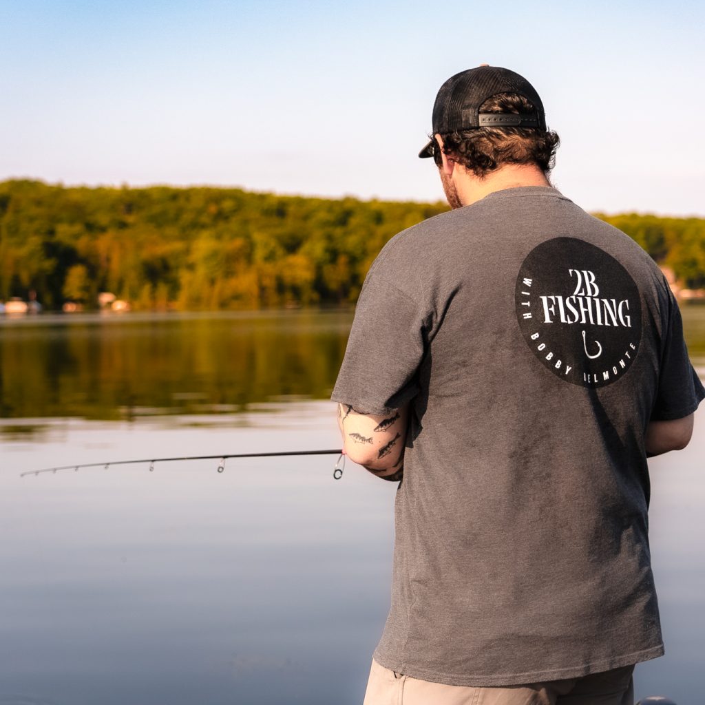 A man with a 2B Fishing shirt casts a line from a dock