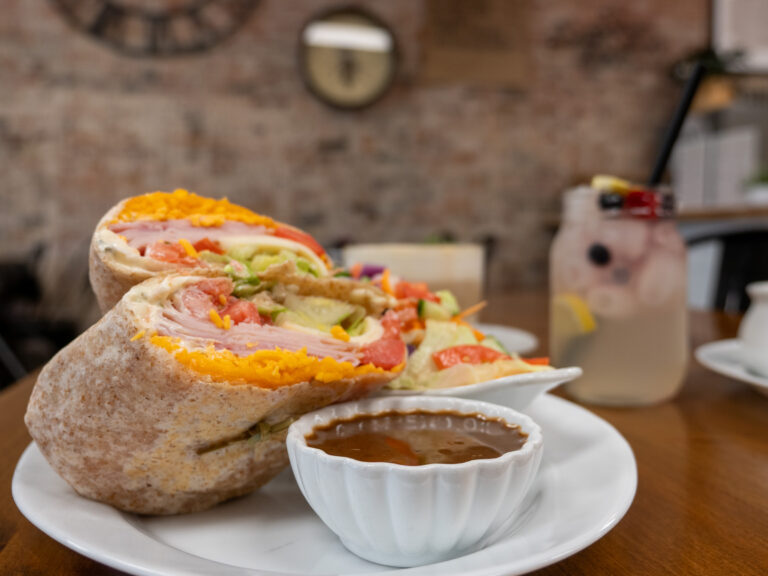 A wrap and side salad, with a dish of dressing