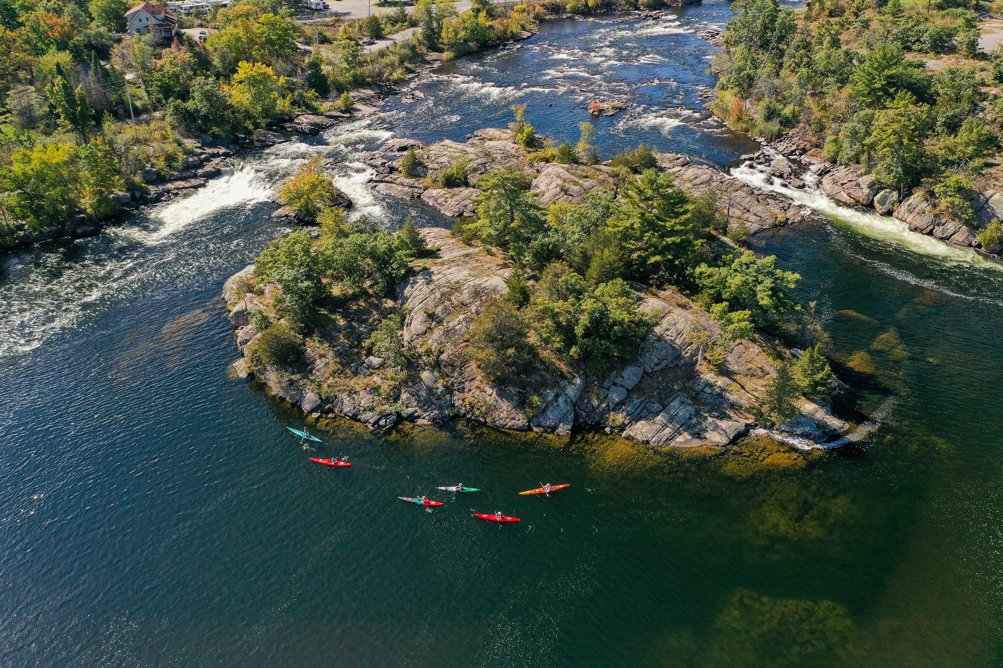 Aerial view of kayakers paddling around a rocky island